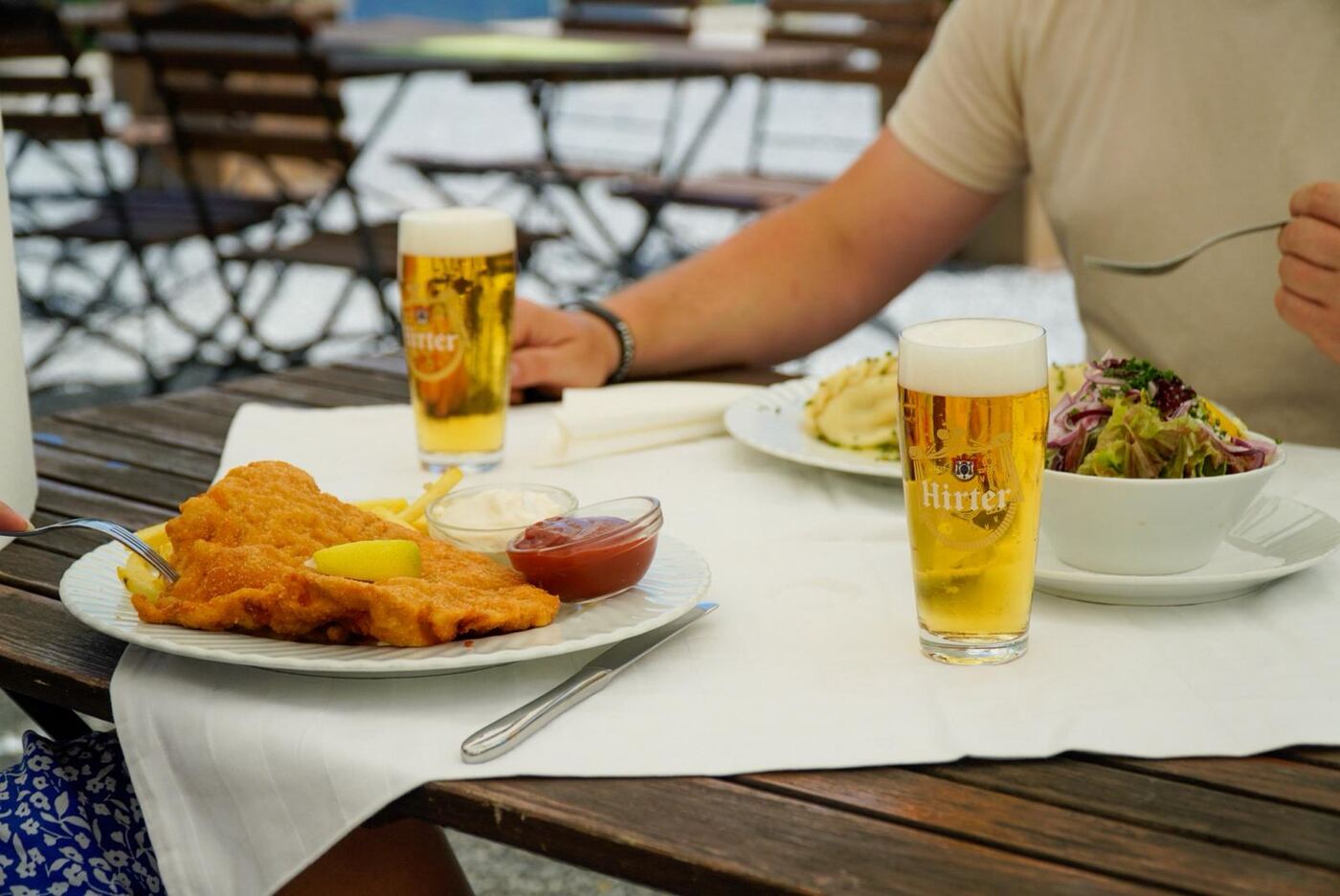 Gäste am Tisch mit Schnitzel und Bier auf der Terrasse